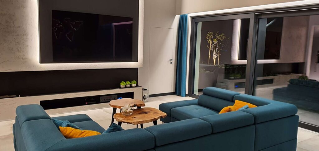 Przestronny salon z turkusową kanapą, przeszkleniami i stylowymi zasłonami - idealne połączenie nowoczesności i elegancji.